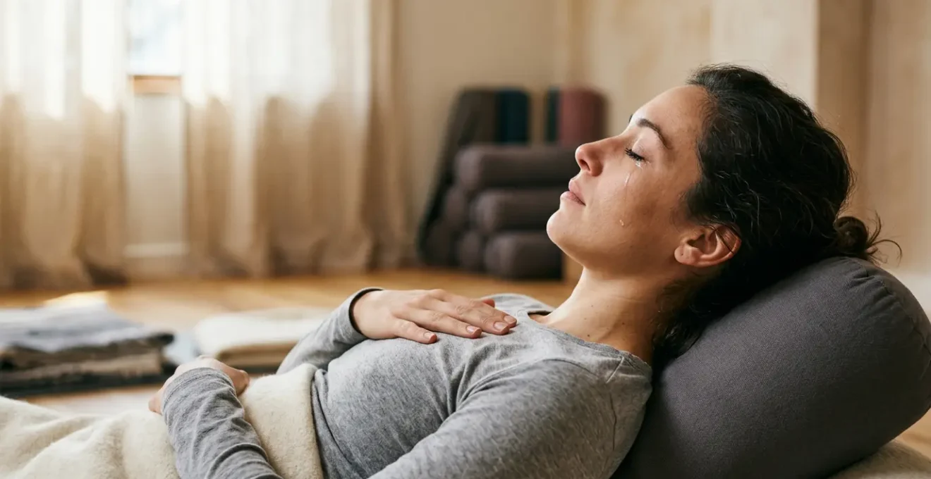 A person experiencing emotional release during a supported restorative yoga pose, showing vulnerability and nervous system safety