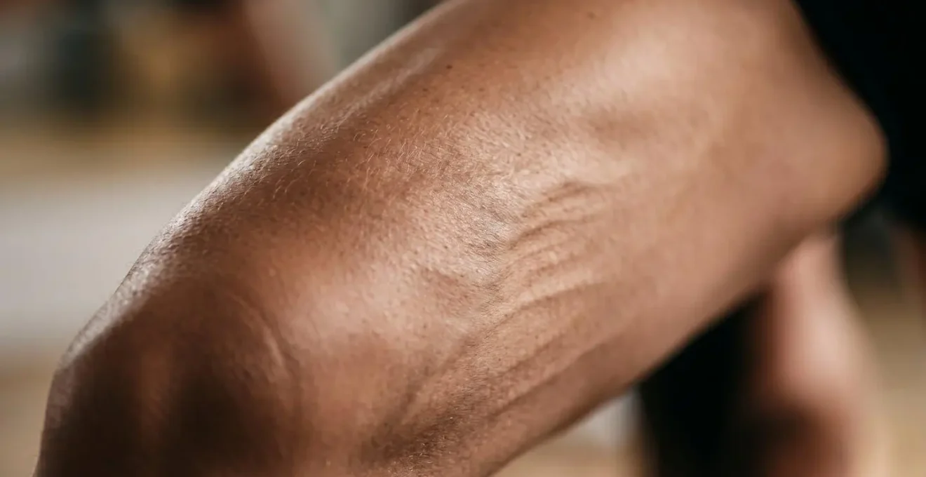 Close-up macro photograph showing engaged quadriceps muscle with visible fiber definition during sustained yoga pose