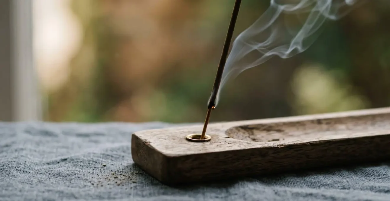 A close-up macro view of a wooden incense holder with gentle smoke wisps rising in soft morning light, representing the sensory anchoring technique for practice rituals